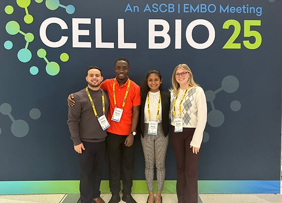 Students and professor standing in front of the CellBio Conference Poster