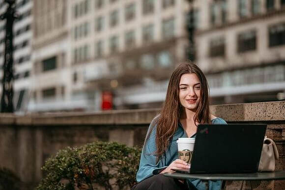 Student working on a laptop in a city