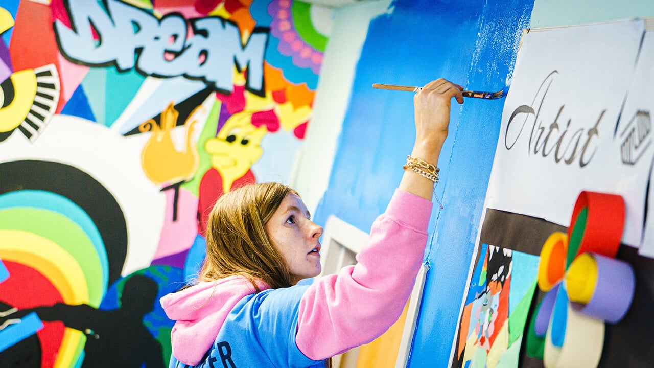 Student painting a colorful wall mural