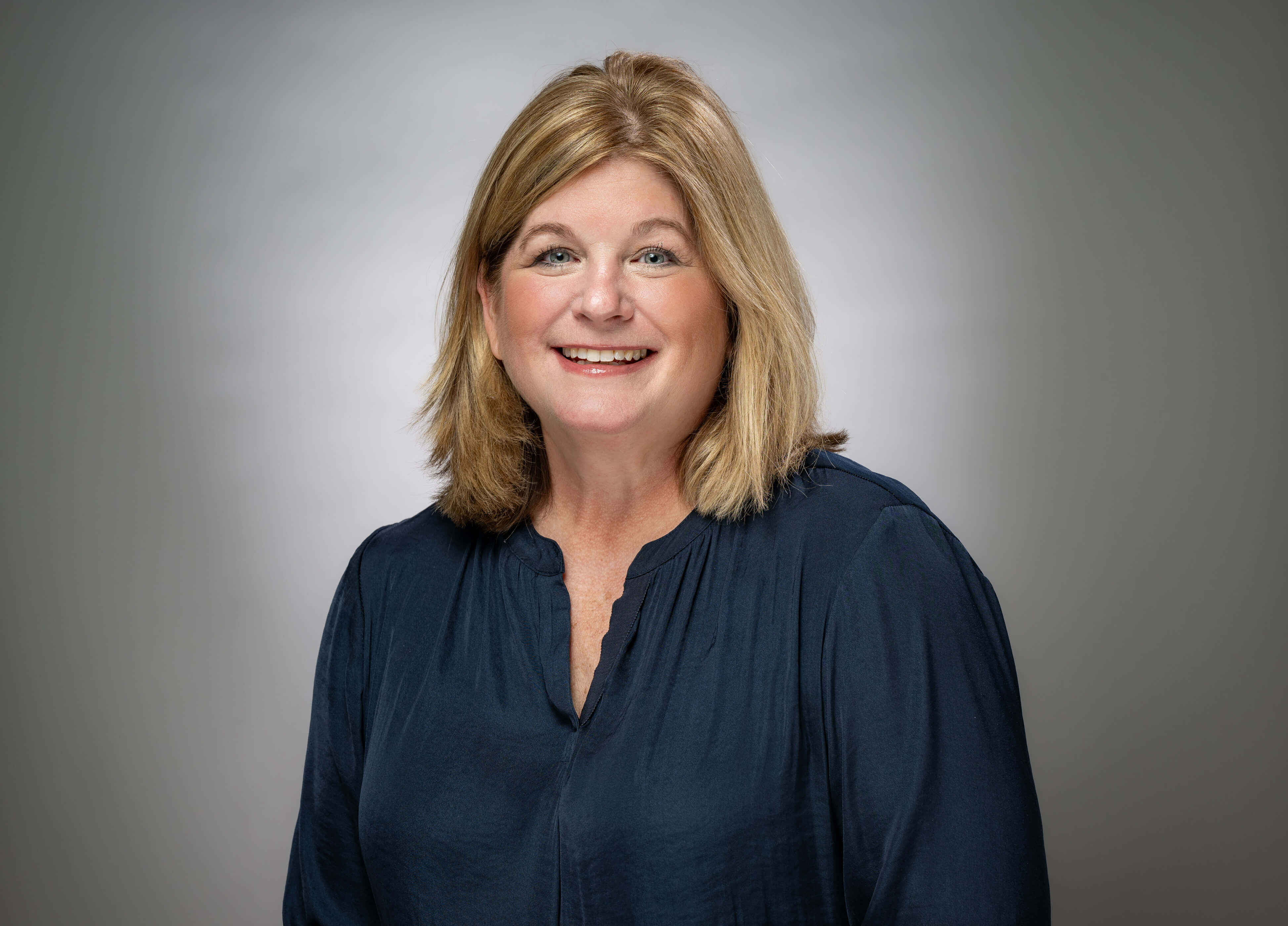 Linda Bedard smiles in front of grey background